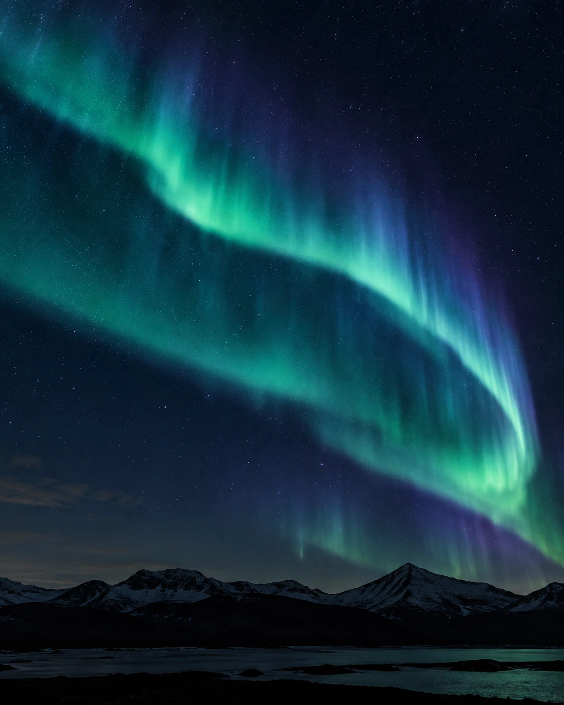 Teal and violet northern lights above a dark mountain range